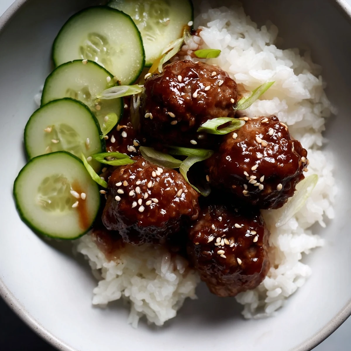 Juicy teriyaki meatball bowls with glistening sauce, rice, and crisp cucumber for a delicious dinner.