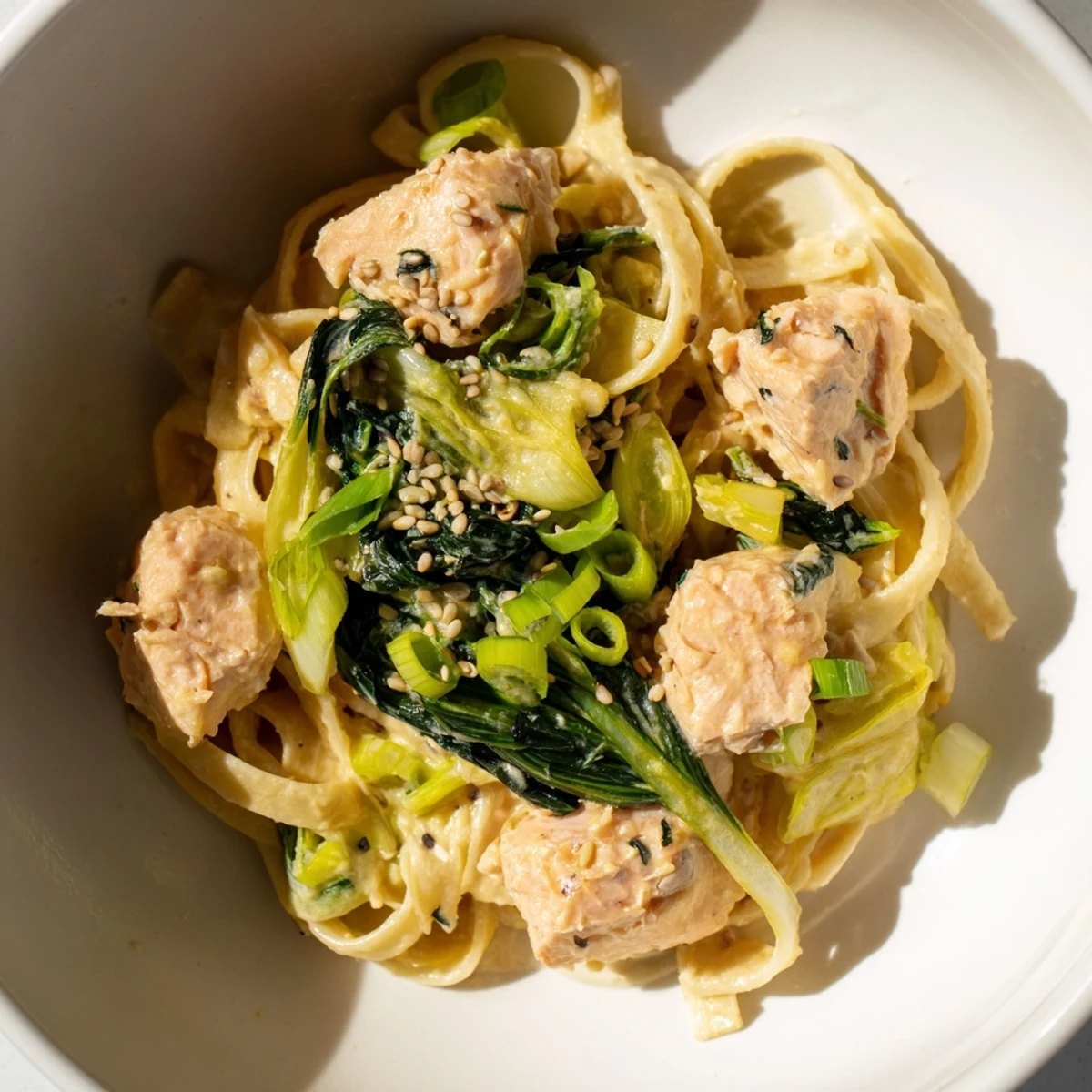 Golden-brown miso butter salmon pasta with flaky salmon bits and vibrant green bok choy.