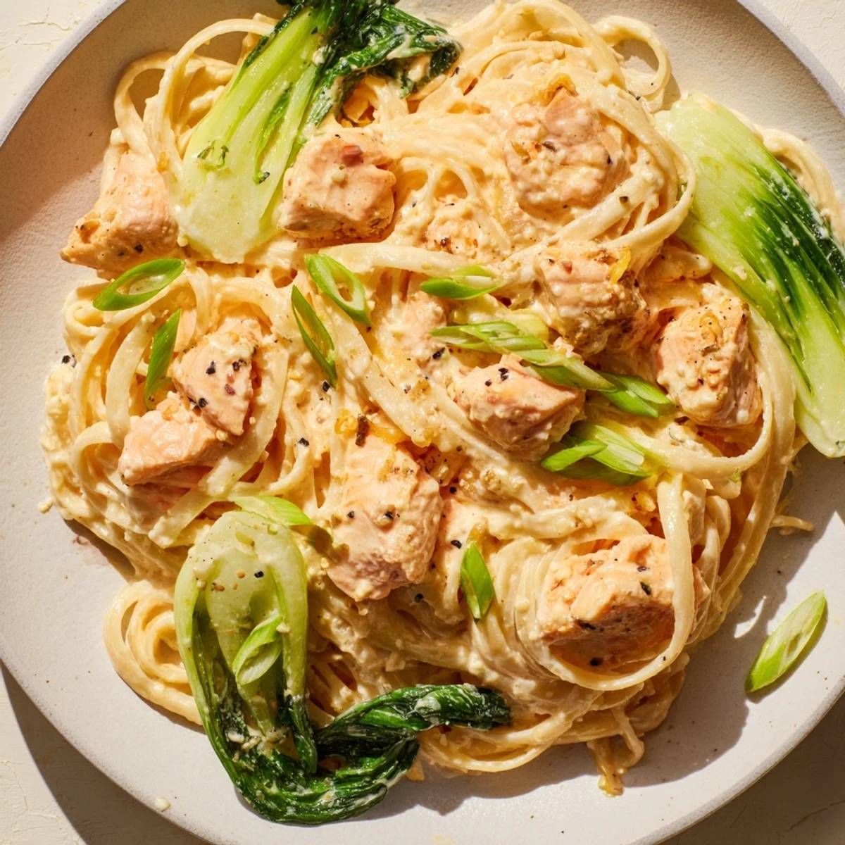 Steaming plate of miso butter salmon pasta, the creamy sauce coating each linguine strand.