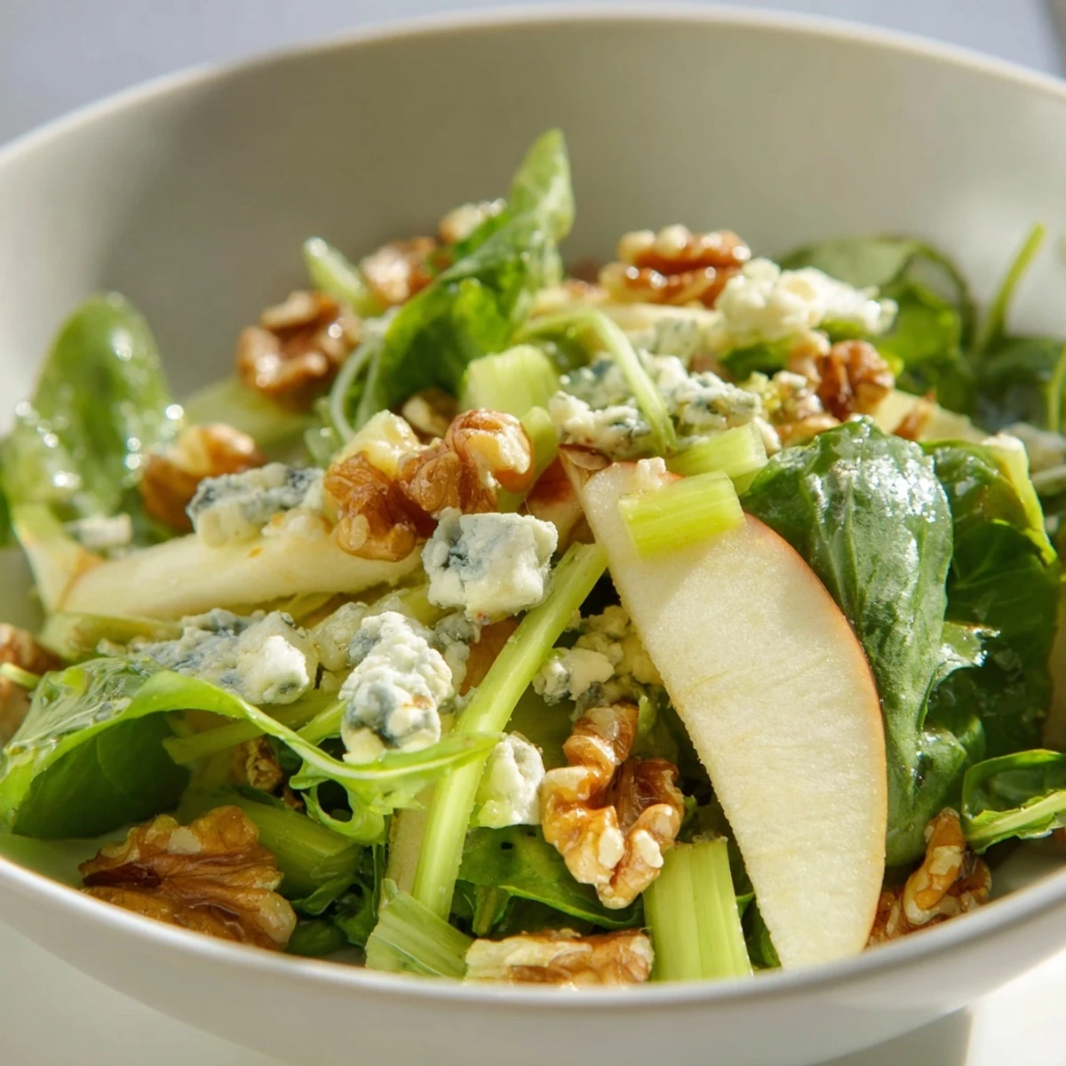 A vibrant Apple and Walnut Salad plated with crumbled blue cheese, celery, and mixed greens, perfect as a light winter side.