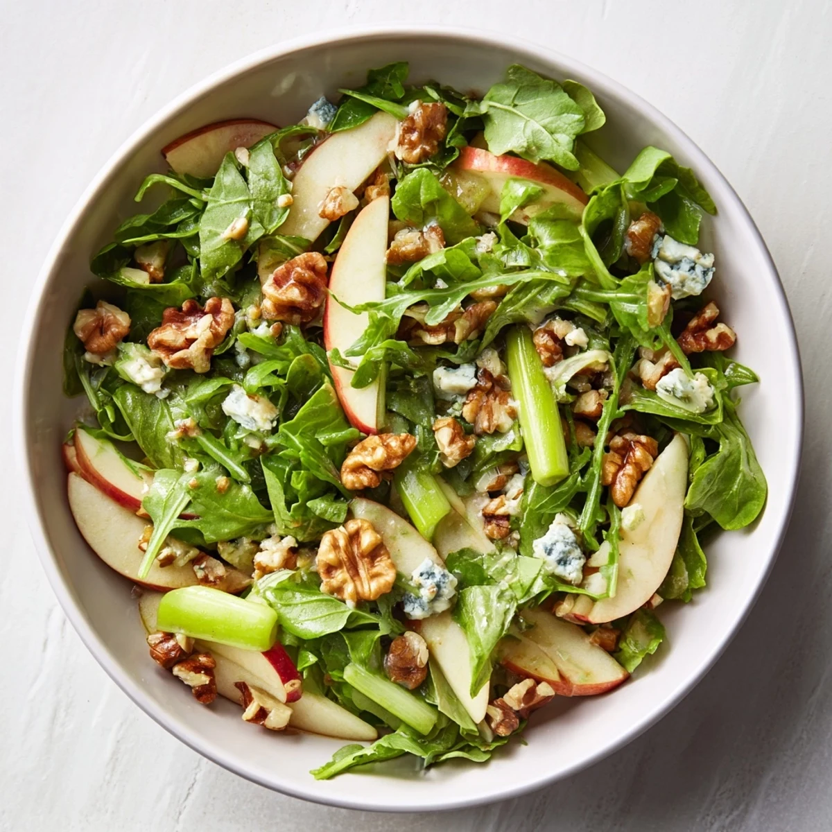 Colorful bowl of Apple and Walnut Salad featuring crisp apple slices, crunchy walnuts, and a drizzle of sweet-tart dressing.