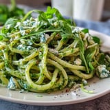 Creamy Linguine with Arugula Pesto served in a white bowl with a lemon wedge.
