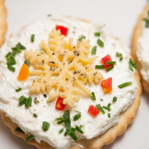 Crisp crackers topped with snowflake cheese designs, these savory bites are perfect holiday appetizers.
