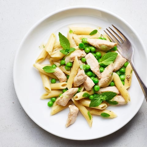 Golden-brown chicken strips mingle with bright green peas and tender penne pasta, all coated in a glossy lemon-mint sauce.