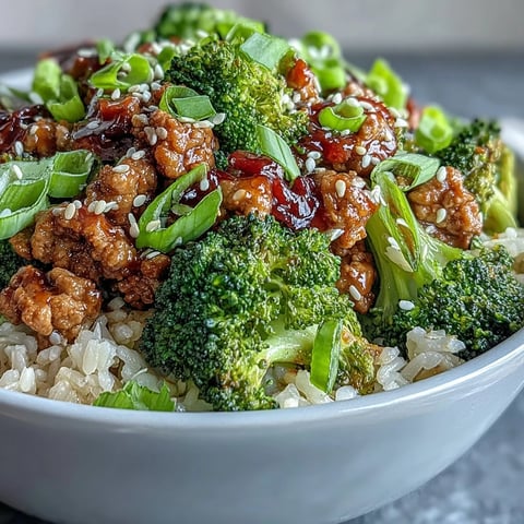 Sweet and Spicy Turkey Broccoli Bowls with steamed broccoli florets and brown rice topped with sesame seeds and green onions.
