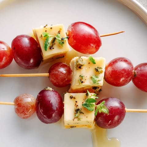 Vibrant skewers of sparkling grape and cheese, drizzled honey, offer a delightful bite for any celebration!