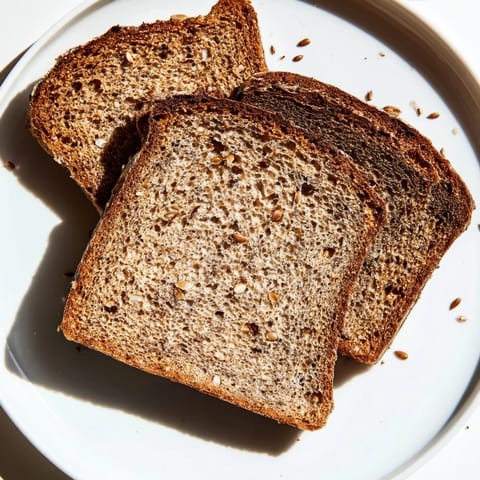 A rustic loaf of Latvian Rupjmaize, boasting a dark, crackling crust, ideal for spreading with butter for breakfast.