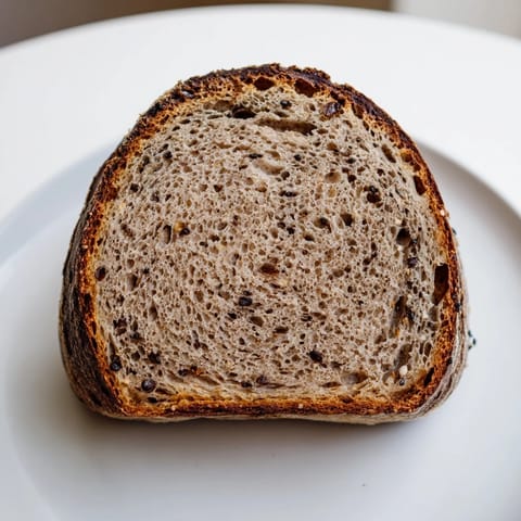 Warm, fresh-baked Estonian Leib sourdough, its deep-brown crust hinting at rye's rich flavor and texture.