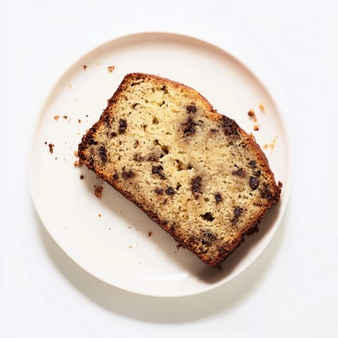 Golden brown banana bread with chopped walnuts, served on a rustic plate with a steaming mug of coffee nearby.