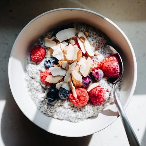 A close-up of chilled Poppy Seed Chia Pudding with a creamy texture, poppy seeds, and a sprinkle of toasted coconut.  